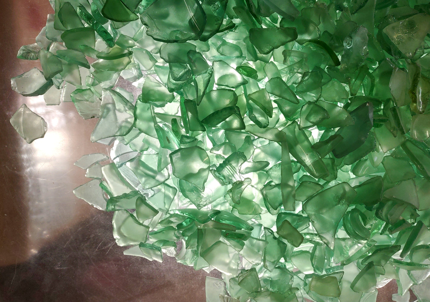 Photo of 10 pound pile of bottle green sea glass. Copyright 2024 Seashellsupply.com.