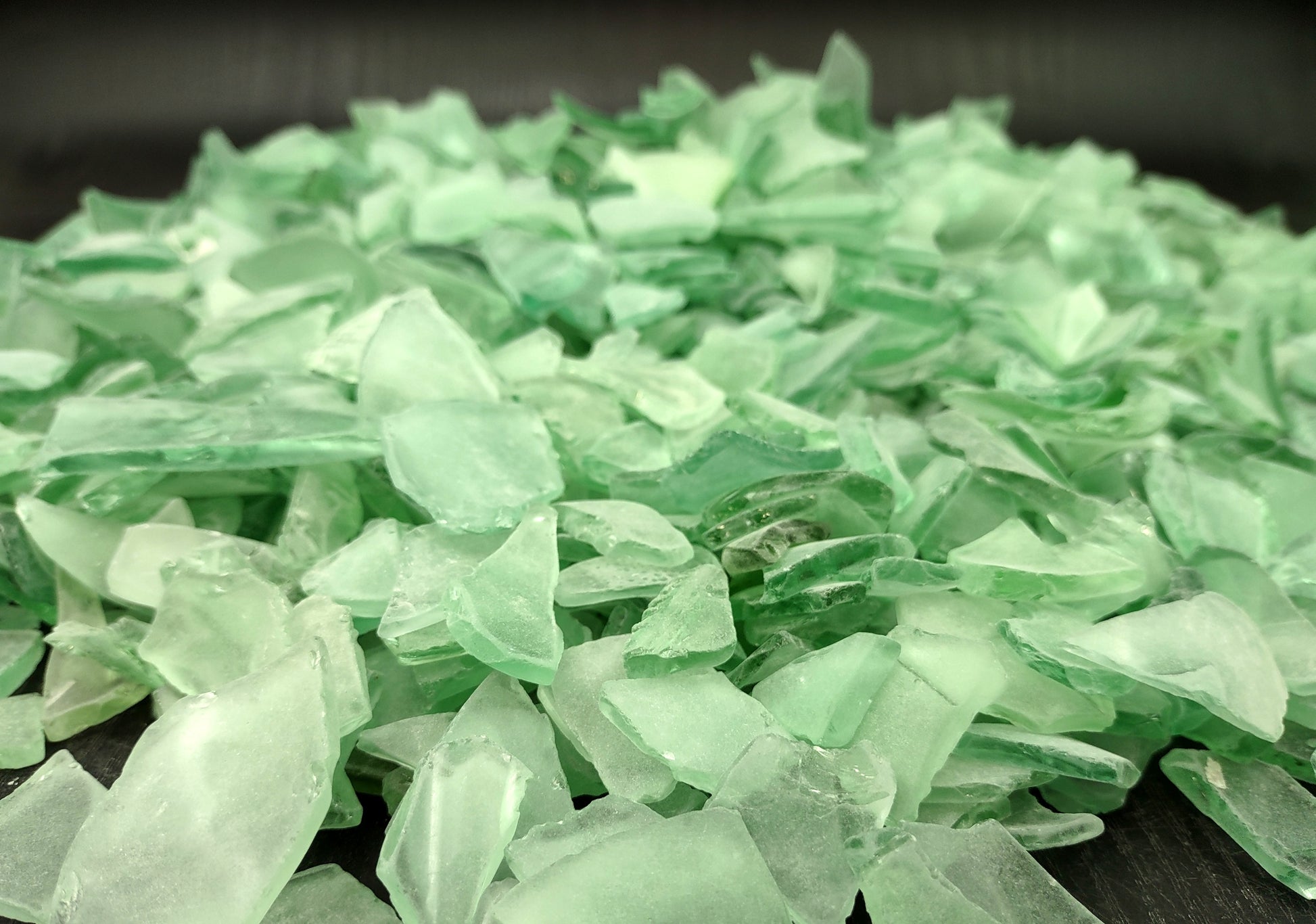 Photo of 10 pound pile of bottle green sea glass. Copyright 2024 Seashellsupply.com.