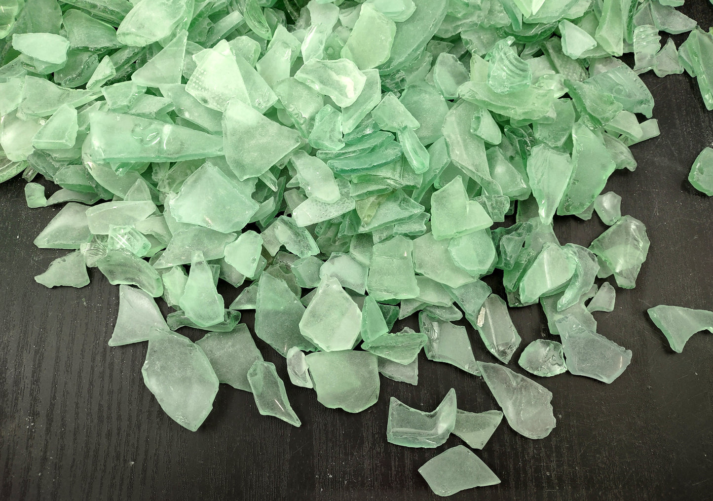 Photo of 10 pound pile of bottle green sea glass. Copyright 2024 Seashellsupply.com.