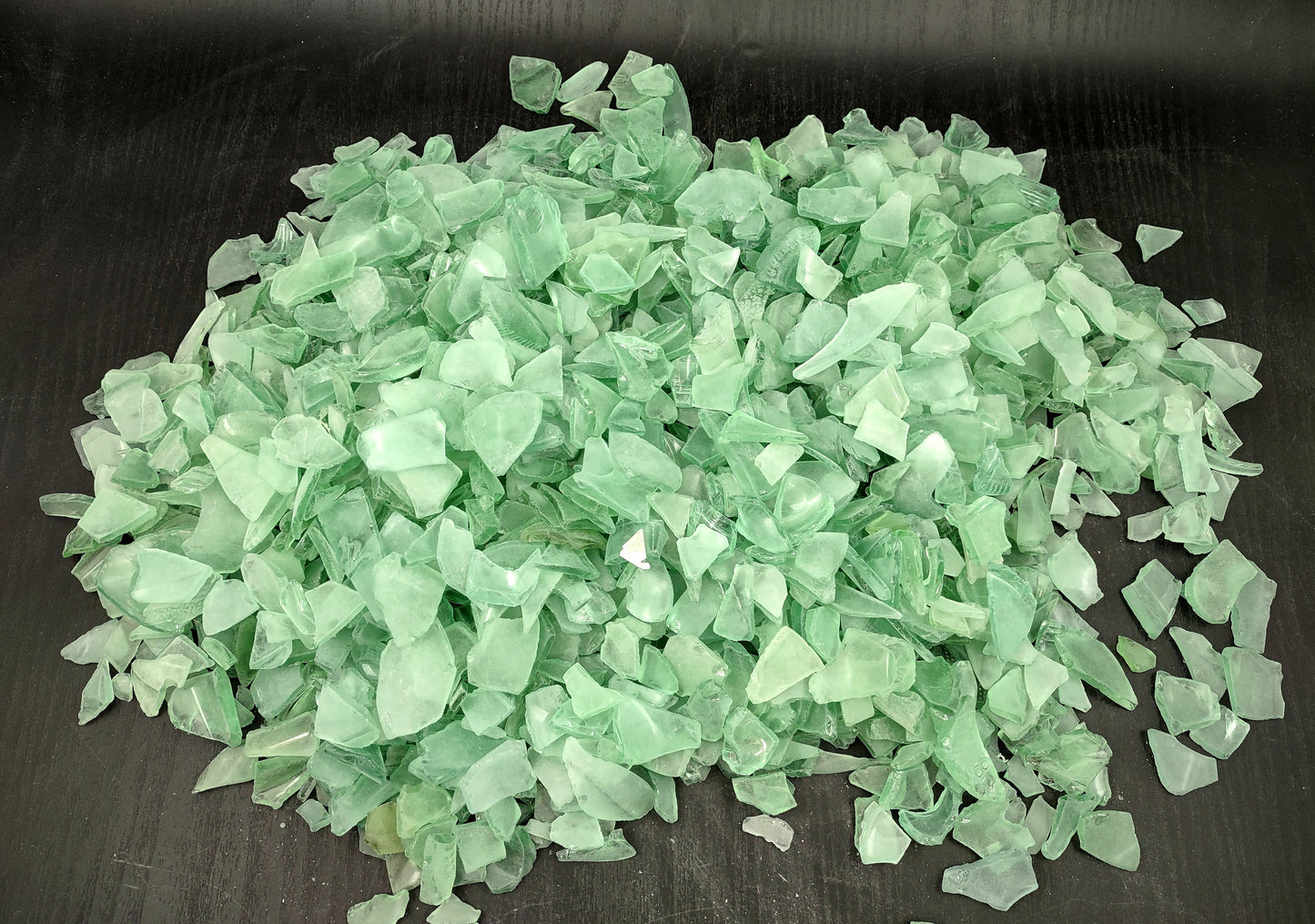 Photo of 10 pound pile of bottle green sea glass. Copyright 2024 Seashellsupply.com.