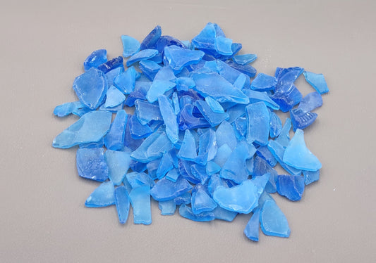 Beach Glass - Medium Tumbled Rough Cobalt Blue - (approx. 1 Kilogram/2.2 lbs. .5-1.25 inches). Multiple shaded blue tiles in a pile, all are different sizes and shapes. Copyright 2024 SeaShellSupply.com.