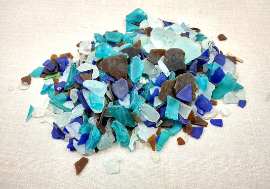 Beach Glass - Medium Tumbled Rough Brown, White & Blue Pacific Assorted - (approx. 1 Kilogram/2.2 lbs. .5-1.25 inches). Multiple blue, white, and brown fragments in a pile. All different shapes and sizes. Copyright 2024 SeaShellSupply.com.