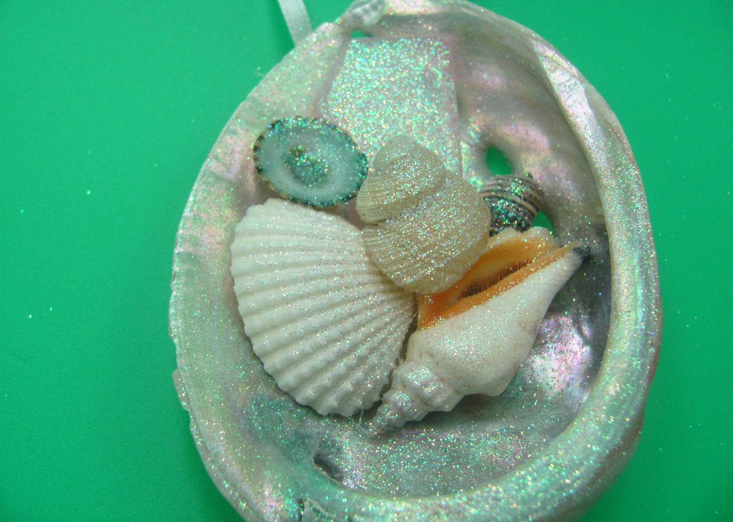 Abalone Frosted Sea Glass Ornament (1 star approx. 3-4 inches) on green background. Copyright 2022 SeaShellSupply.com.