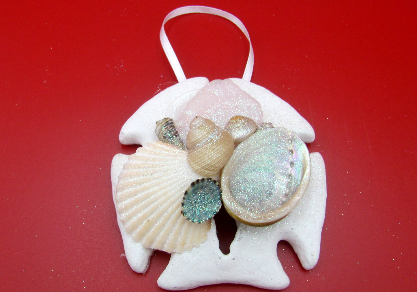 Frosted Sea Glass Sand Dollar Ornament (1 sand dollar approx. 3-4 inches) on red background. Copyright 2022 SeaShellSupply.com.